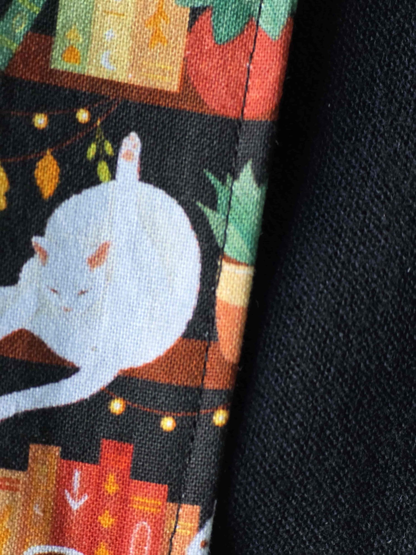 Zoom sur les détails du couvre-livre artisanal ajustable aux nombres de pages et à l'épaisseur du livre. Motif tissu en coton chat bibliothèque. Flanelle de coton noire