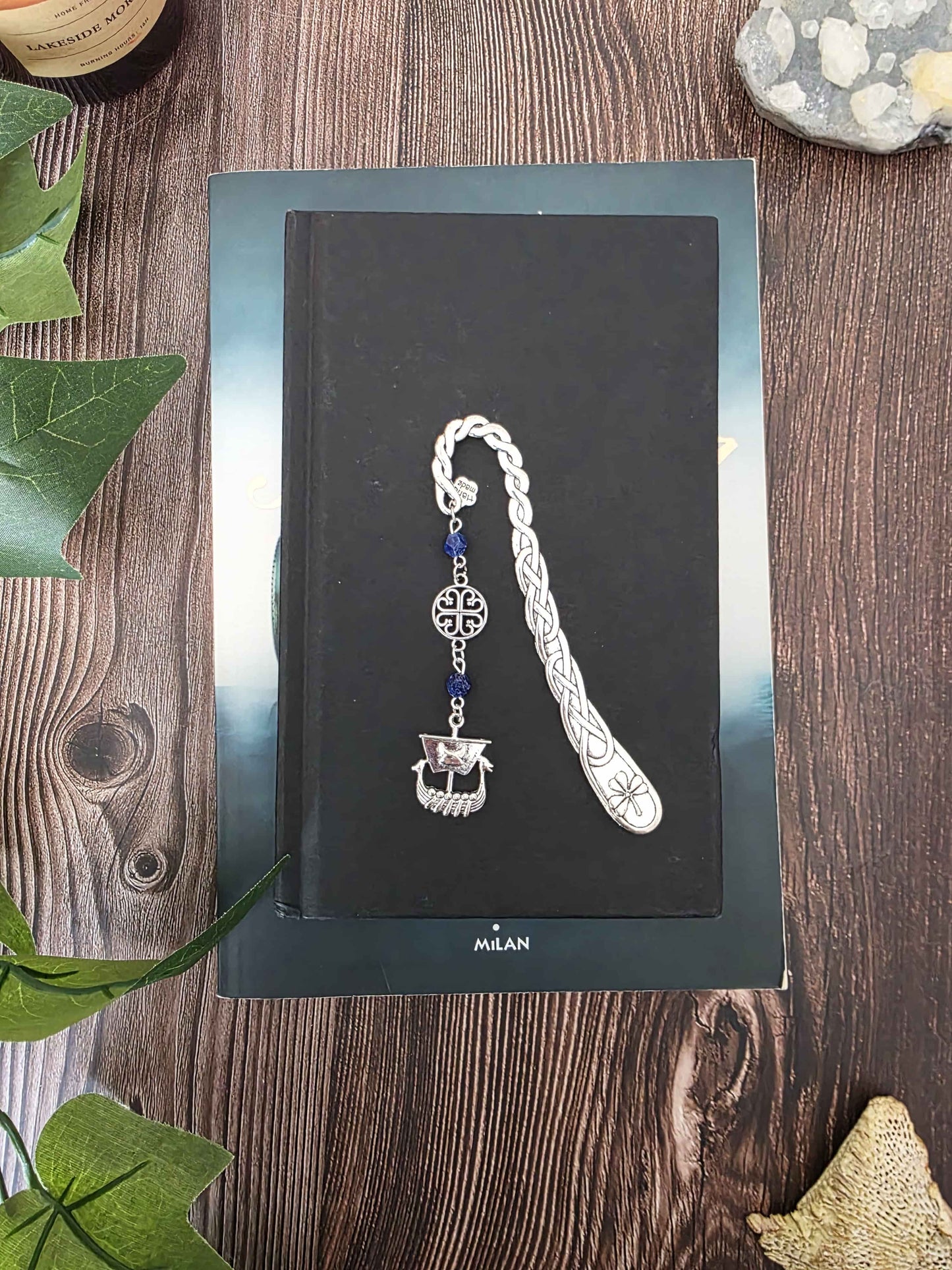 Marque-page en métal dragon oriental avec des pierres naturelles oeil-de-tigre. Les pierres sont personnalisables. Bellette Workshop. Metal bookmark with gemstones. sur un livre noir