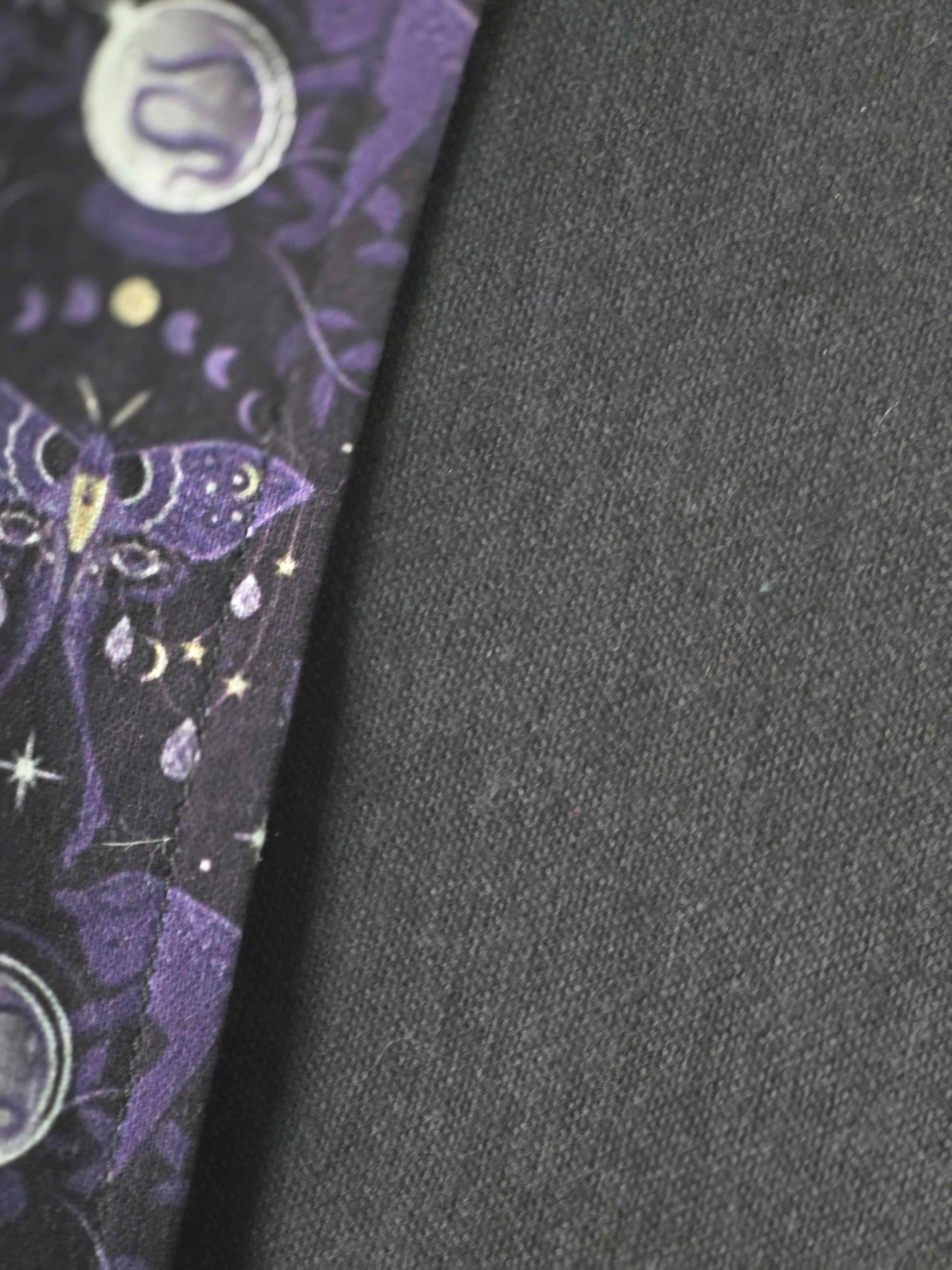 Zoom sur les détails du couvre-livre artisanal ajustable aux nombres de pages et à l'épaisseur du livre. Motif tissu en coton chat  ésotérique, lune d'améthyste et flanelle de coton noire