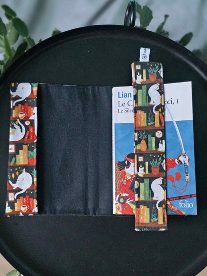 Couvre-livre artisanal ajustable aux nombres de pages et à l'épaisseur du livre. Motif tissu en coton chat bibliothèque avec son marque-page en tissu assorti. Ouvert sur la flanelle noire en coton toute douce