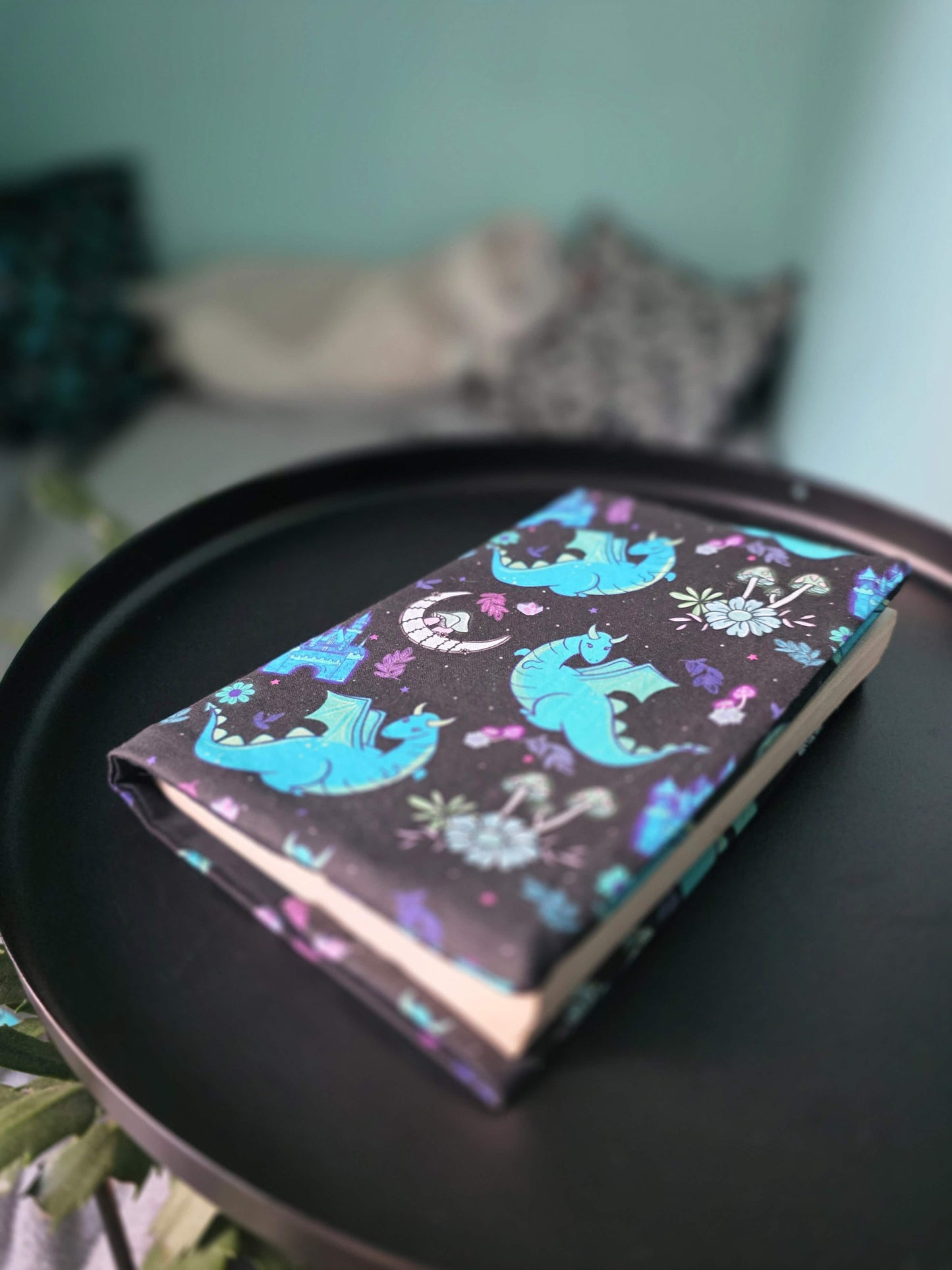Couvre-livre artisanal avec motif dragon fantasy posé sur une table noire 