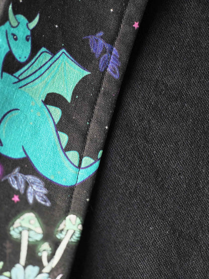 Détail du tissu coton motif fantasy et dragons et éléments magique ainsi que de la doublure en flanelle de coton noire