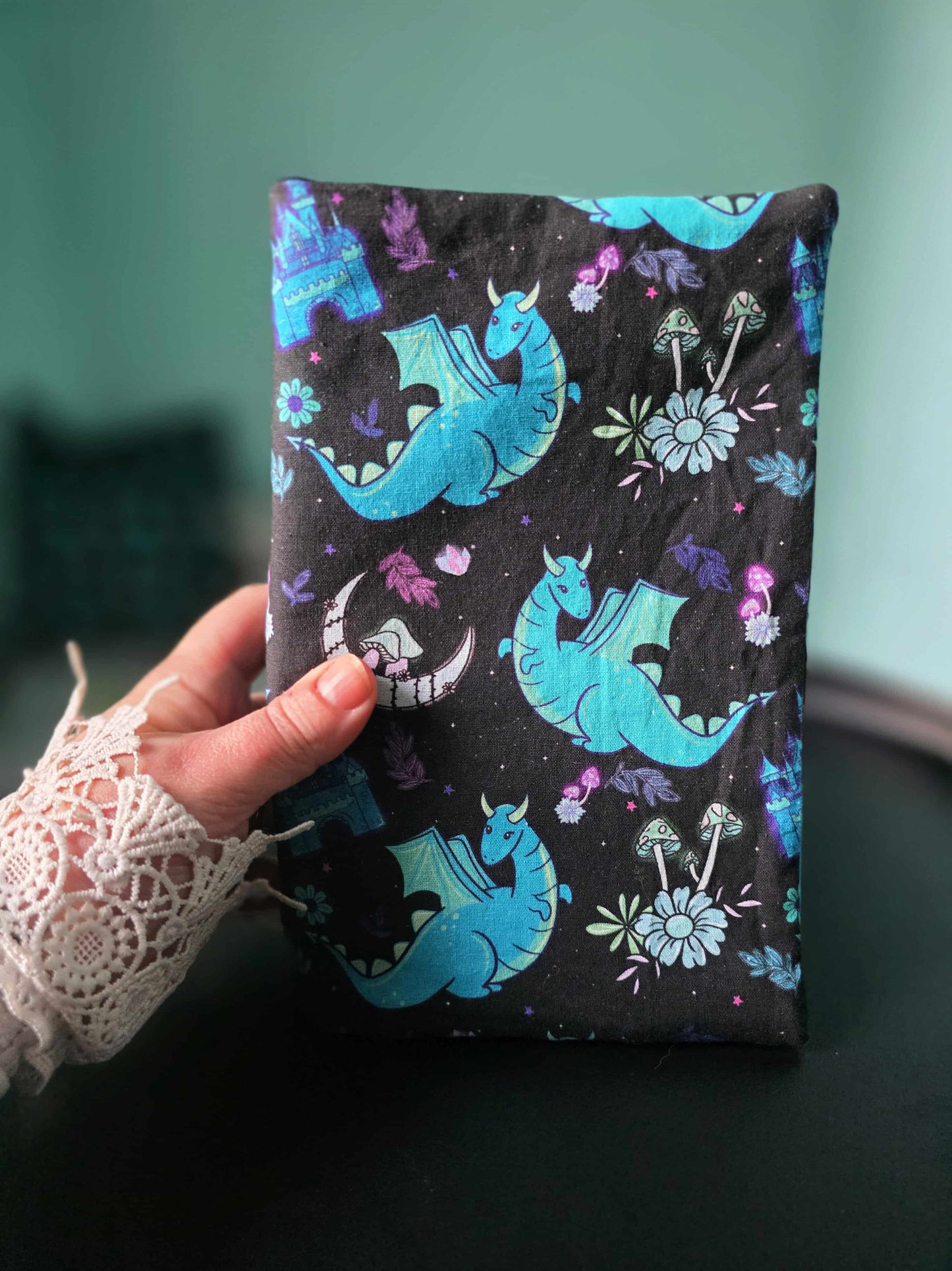 Couvre-livre en tissu fait main ,format broché, poche et relié tenu en main pour montrer la taille réelle