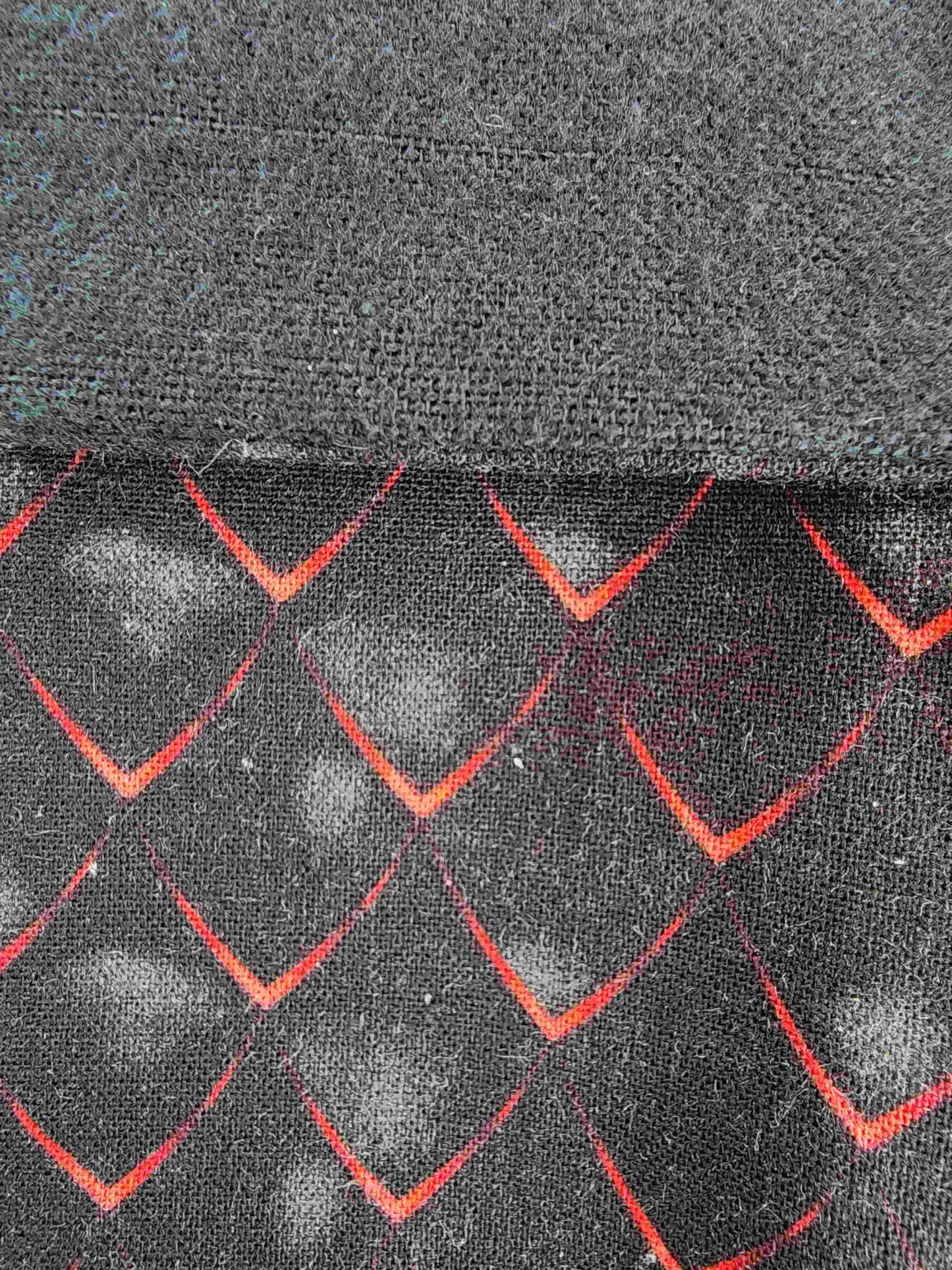 Détail du tisus écaille noir et rouge d'inspiration dragon, couture artisanale visible et flanelle de coton noire visible.