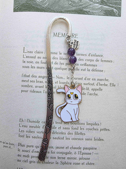 marque page en metal inspiré par les manga. Chat noir et chat blanc. Artemis et Luna. Pierres naturelles personnalisables. Améthyste sur le modèle. Fait main en France. Bookmark. Metal bookmark. chat blanc uniquement posé dans un livre