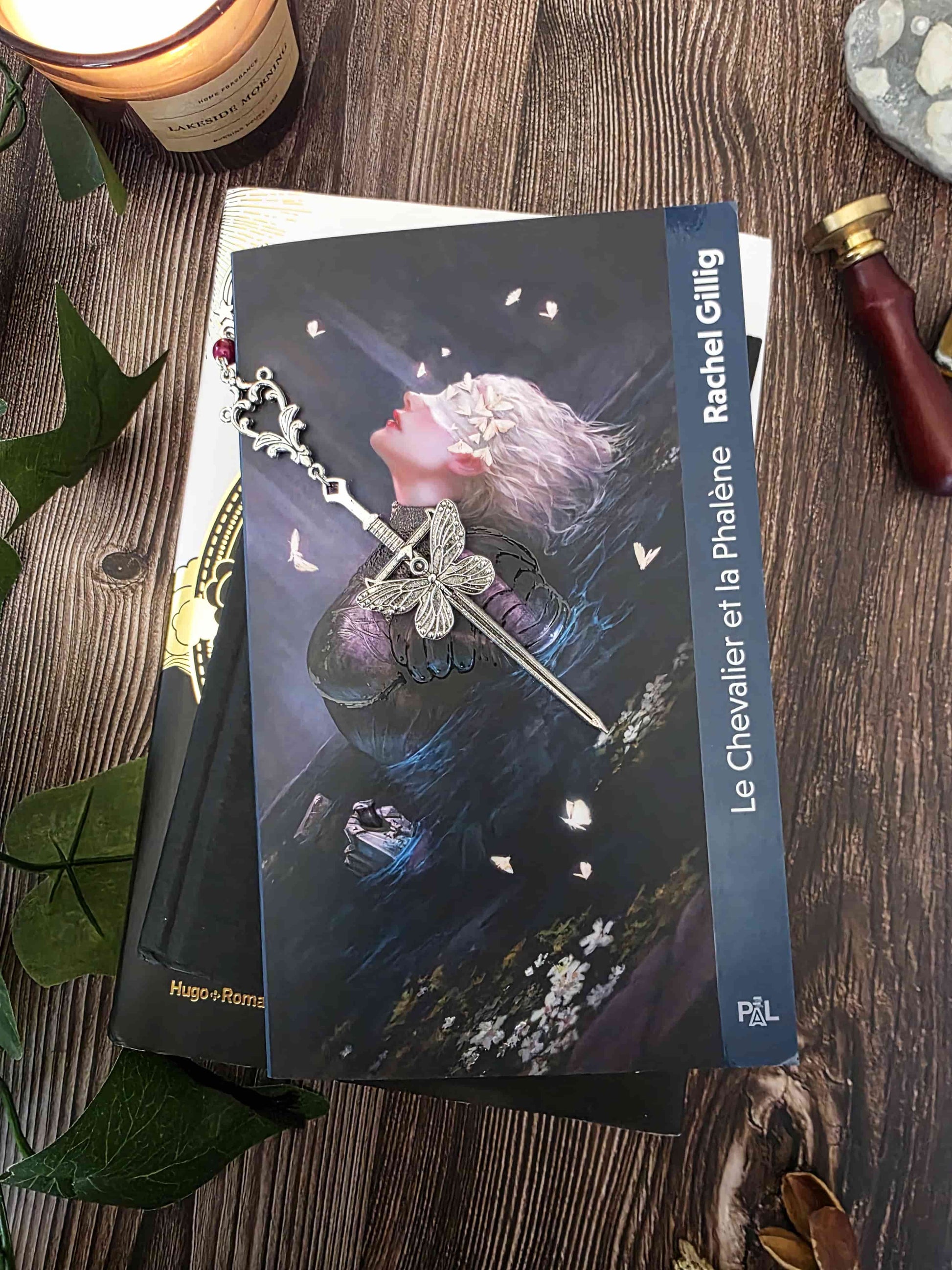 marque-page en métal d'une épée avec un gros papillon. Entrelacs. Inspirée par la fantasy, romantasy, dark fantasy. Fait main par belletteworkshop. pierre naturelle d'oeil de tigre rose, personnalisable. posé sur le livre le chevalier et la phalène. 