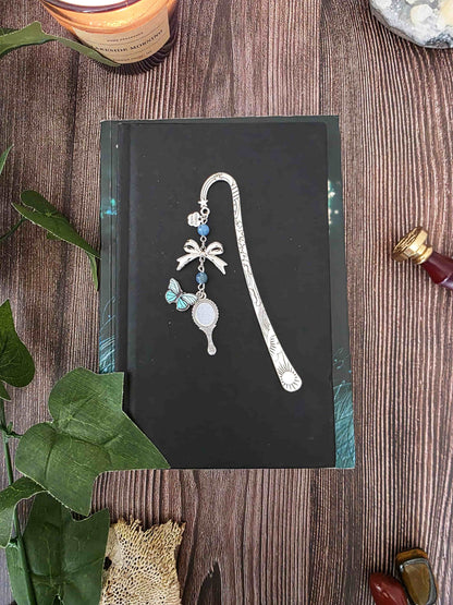 marque-page miroir enchanté, papillon bleu avec un ruban et deux pierres naturelles d'apatite bleue. Le signet est fait à la main par bellette workshop. Ce bijou de lecture est personnalisable