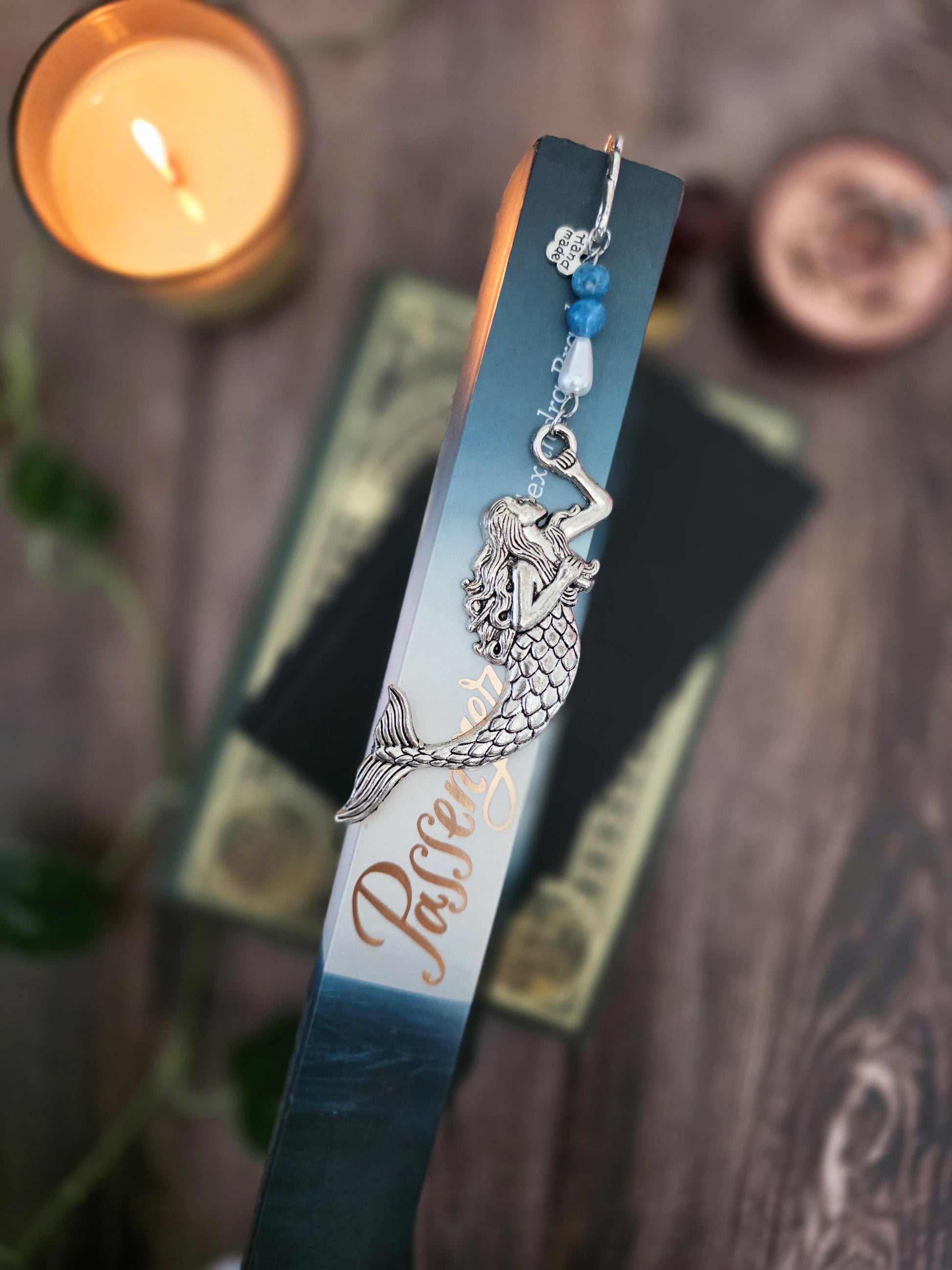 marque page en metal sirene, gardienne des abysses. Avec des pierres bleues d'apatite bleue et une goutte blanche. Pierres naturelles personnalisables. Signet artisanal Bellette Workshop. vu dans la  tranche d'un livre sur la mer
