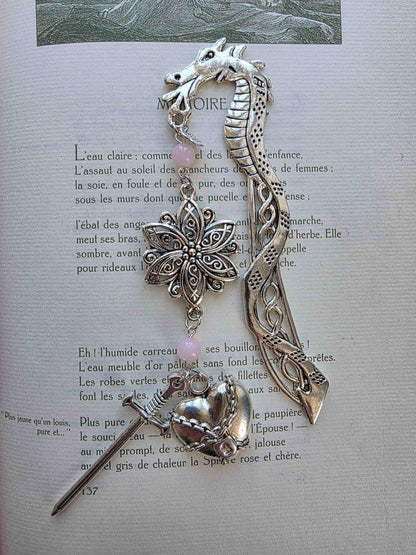 marque page metal avec une tige dragon, une fleur ciselée, une épée et un coeur brisé. Pierres naturelles de quartz rose personnalisable. Bellette Workshop. Fait main. Metal bookmark fantasy. Dark fantasy. Amour brisé. Cadeau fait main original pour lecteur et lectrice vu à plat