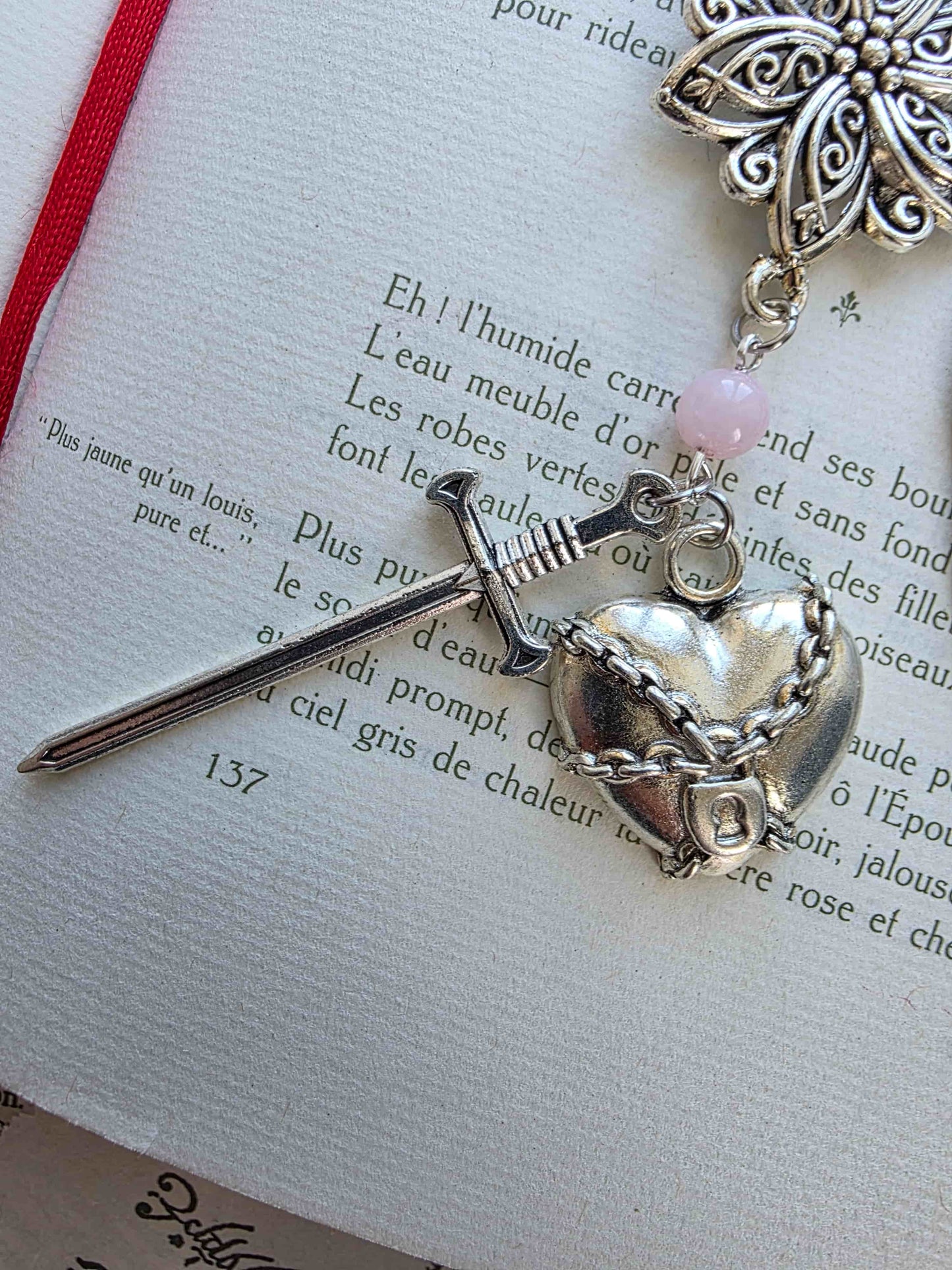 marque page metal avec une tige dragon, une fleur ciselée, une épée et un coeur brisé. Pierres naturelles de quartz rose personnalisable. Bellette Workshop. Fait main. Metal bookmark fantasy. Dark fantasy. Amour brisé. Cadeau fait main original pour lecteur et lectrice vu coeur enchainé et épée 