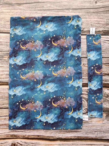 pochettte à livre, booksleeve, en tissu avec un joli ciel étoilé avec des lunes dorées. Fait main en Bretagne par Bellette Workshop. Avec un marque-page en tissu assorti en option possible.