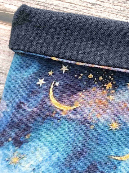 Zoom de la pochettte à livre, booksleeve, en tissu avec un joli ciel étoilé avec des lunes dorées. Fait main en Bretagne par Bellette Workshop. Flanelle de coton noire pour la doublure intérieure.