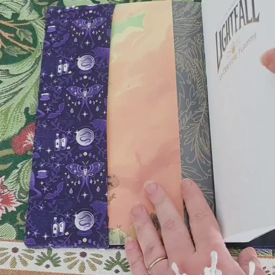 Vidéo de 10 secondes faisant la démonstration du couvre-livre artisanal ajustable aux nombres de pages et à l'épaisseur du livre. Motif tissu en coton chat  ésotérique, lune d'améthyste avec son marque-page en tissu assorti. 